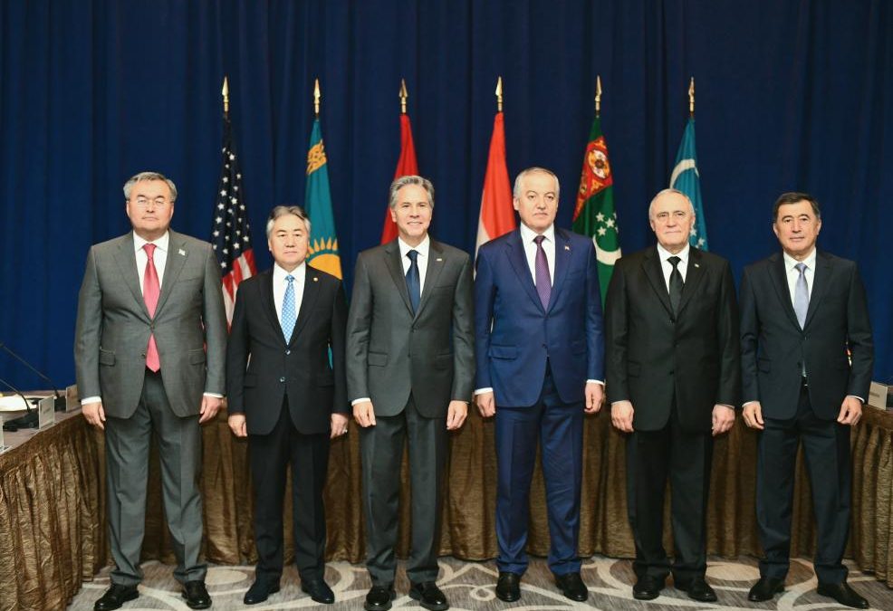 Five Dignitaries stand in front of the flags of the United States, Kazakhstan, Kyrgyzstan, Tajikistan, Turkmenistan and Uzbekistan